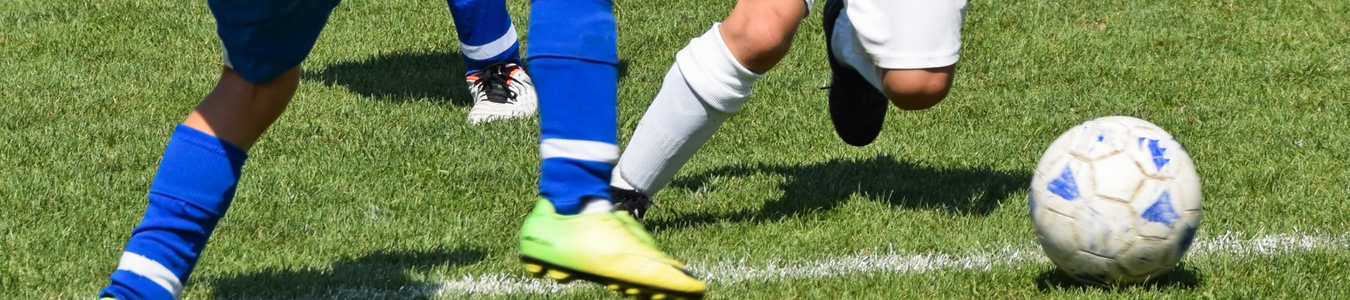 boys feet on grass playing soccer blue socks lime green soccer shoes